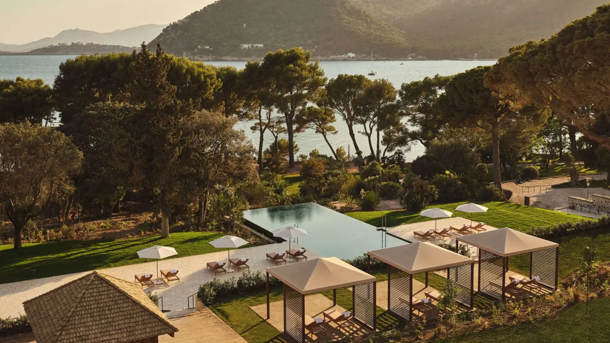Aerial view of a resort infinity pool and cabanas overlooking a coastal bay